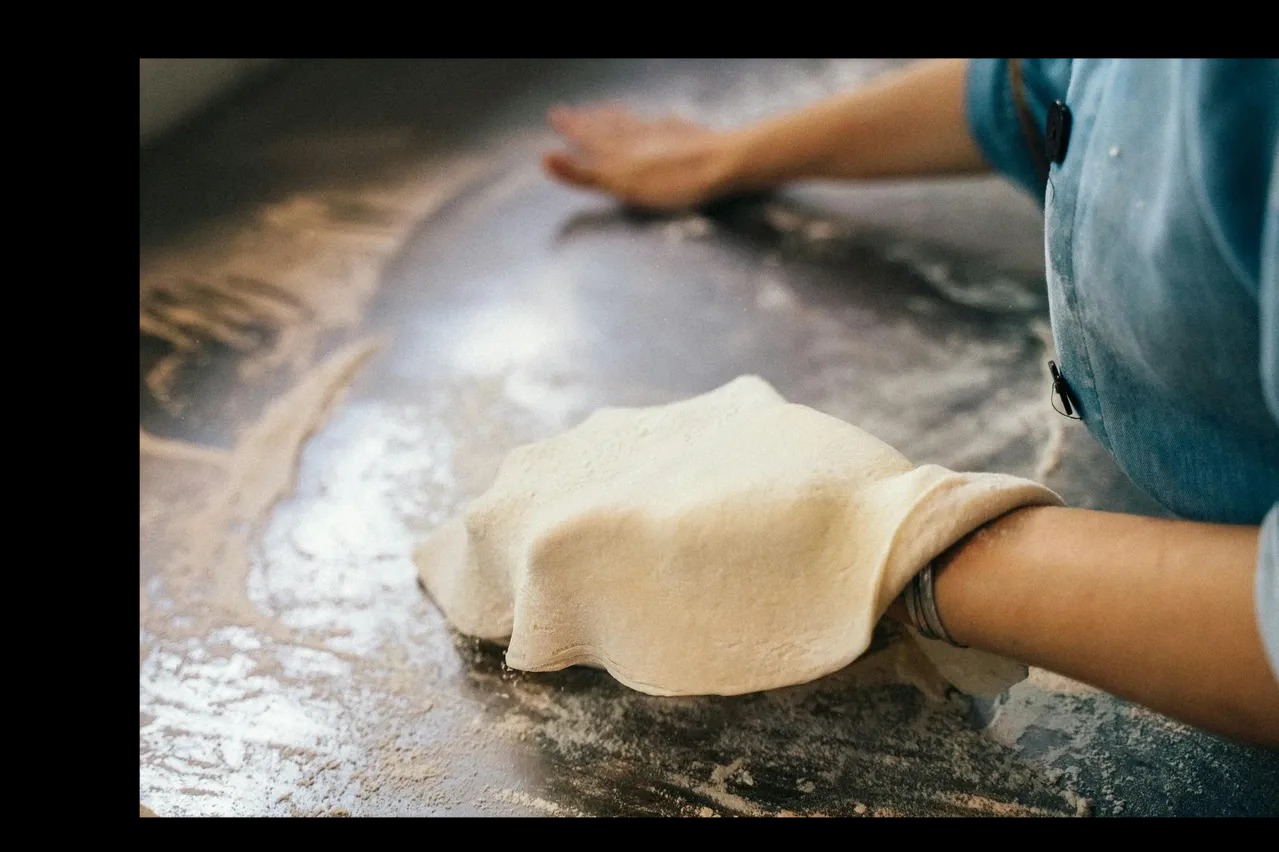 Hands stretching pizza dough at Pizza Dojo pizza making workshop Kolkata
